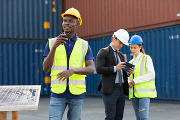 African factory worker or engineer using walkie talkie for preparing a job in containers warehouse storage