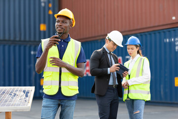 African factory worker or engineer using walkie talkie for preparing a job in containers warehouse storage