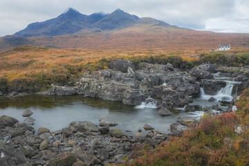 Scenic landscape view of the Black Cuillin mountains and a lone white croft house cottage at Sligachan waterfall on the Isle of Skye, Scottish Highlands, Scotland. © Stephen