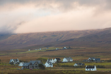 Moody, dramatic golden light over rural countryside landscape of Trotternish Ridge and Staffin village on the Isle of Skye, Scotland. - obrazy, fototapety, plakaty