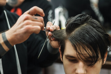 Fototapeta premium Hipster client man visiting in barber shop shaving hair. Modern guy having his hair cut in barbershop.