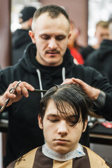 Hipster client man visiting in barber shop shaving hair. Modern guy having his hair cut in barbershop.