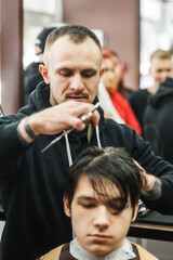 Obraz premium Hipster client man visiting in barber shop shaving hair. Modern guy having his hair cut in barbershop.