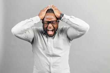 Mad frustrated black guy holding head and screams isolated on grey, angry African-American man with suffering face expression feels disappointment and depression, yelling with eyes closed - Powered by Adobe