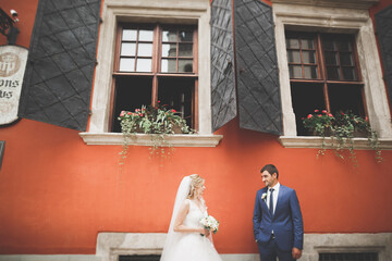Lovely happy wedding couple, bride with long white dress posing in beautiful city