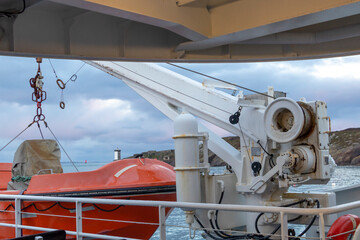 Liferaft, orange lifeboat ready for evacuation from the board, hanging on the side of a cruise ship
