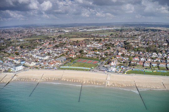 Felpham seafront in West Sussex with colourful beach huts on the coast and tennis courts in the background. Aerial View.