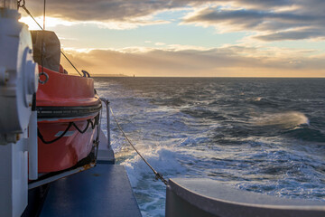 Liferaft, orange lifeboat ready for evacuation from the board, hanging on the side of a cruise ship