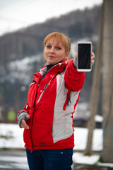 A girl in a winter red sports jacket with a phone in her hand.