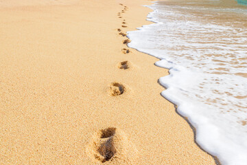 footprints on the yellow sand beach with white foam