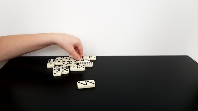children play a board game. hands lay out dominoes