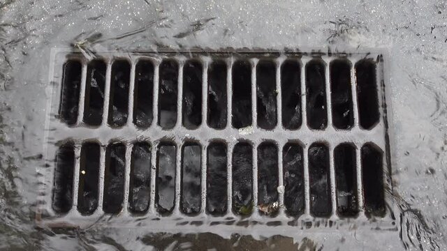 Rainwater pouring into road storm drain 