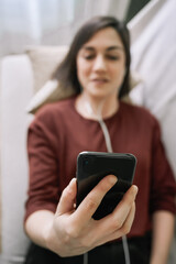 Fototapeta na wymiar Woman hand lying on a sofa at home holding a black mobile while making a video call
