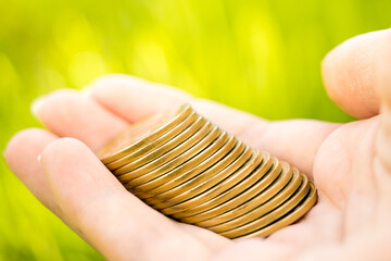 Silver coins in hand on natural green background