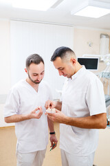 Dentists doctors stand in the office, clinic with a chair, tools. Dentist workplace. Orthodontists hold in their hands and examine the cast of the jaw. Dentistry concept.