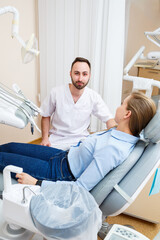 A professional dentist communicates with a woman patient. Dental office for patient examination. Discussion of the dental treatment process.