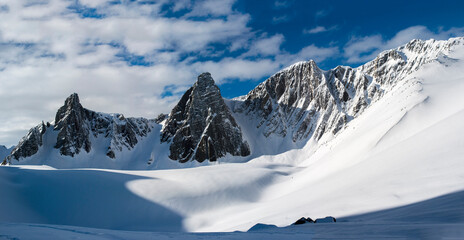 Panorama of snowy peaks under blue sky with clouds 