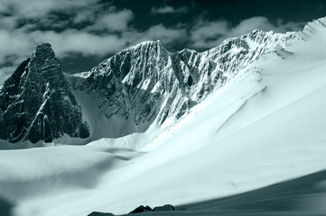 snow covered mountains in winter in black ands white with dramatic sky 