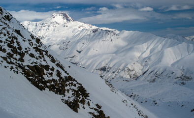 snow covered mountains with top peak of Kazbegi in a distance with blue sky with clouds 
