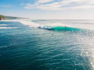 Blue wave with surfers in ocean, drone shot. Aerial view of waves