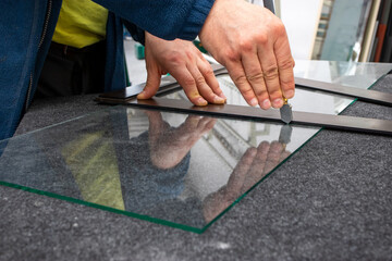 The glazier cuts the glass with a hand-held cutting tool. Handicraft plant, Close up