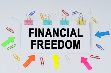 On the table there are paper clips and directional arrows, a sign that says - FINANCIAL FREEDOM