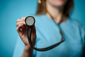 A doctor on a blue background holds a stethophonendoscope. Close-up