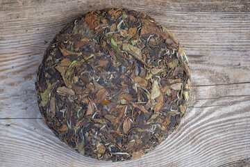 natural Chinese white tea in the form of a pancake. pressed round tea on a wooden stand