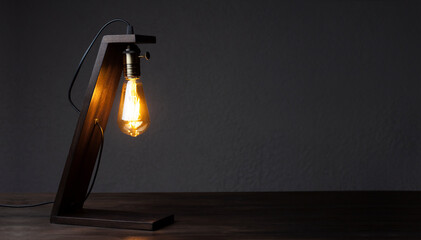 Table lamp on the table. Wooden decorative lamp Edison. Night light in the dark.