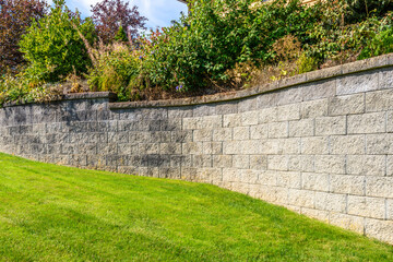 Stone fence with green lawn and landscape