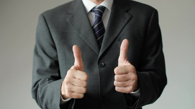 Close up of successful business man giving two thumbs up showing approval. Businessman, boss, and entrepreneur with positive gesture signaling OK, all right, and satisfaction.