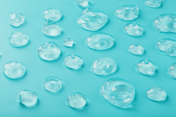 Drops of Gel with hyaluronic acid in the form of a smear of glossy texture on a cyan background.