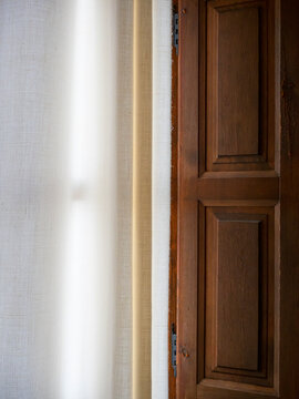 La luz penetra entre los visillos de una ventana de madera