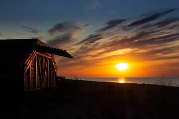 Sunset, sunrise on the calm sea with a hut