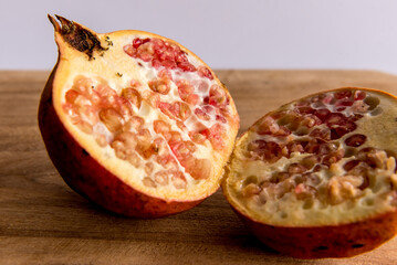 Pomegranate fruit cut in half on white background.