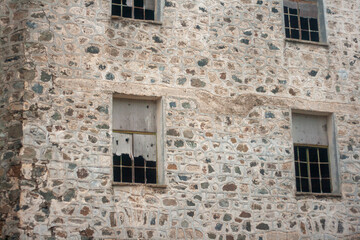 Old ruined abandoned dark brick wall with broken windows 
