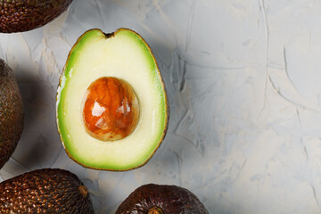 Avocado halves with whole Hass fruits on a background of gray concrete, stone or slate.
