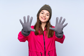 Young girl with winter hat isolated on blue background counting ten with fingers