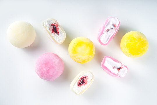 Traditional Japanese dessert mochi. Colorful mochi ice cream on a white table, whole and cut with berry, fruit filling