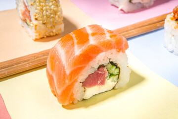 Sushi rolls set with rice and fish and chopsticks on various colorful bright backgrounds, trendy dark shadows flatlay