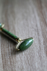Jade face roller on wooden background. Selective focus.