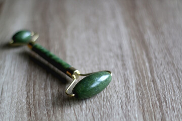 Jade face roller on wooden background. Selective focus.