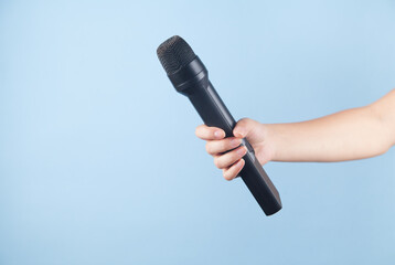 Microphone in a girl's hand on a blue background.