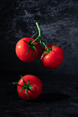 Red ripe tomatoes levitating on a dark background close-up.