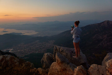 Beautiful girl photographing mountain sunset