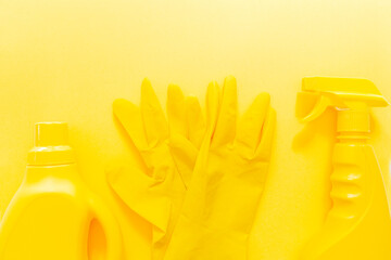 Yellow onochrome flat lay of cleaning tools. Colorful rubber gloves, spray, gel bottle