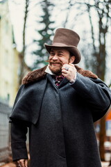 1900 style man wearing black hat and coat. Man in Dickens style. 