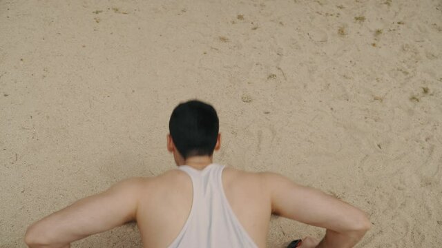 hombre haciendo flexiones sobre la arena, hombre musculoso con camiseta blanca haciendo ejercicio, vista a&eacute;rea del hombre haciendo flexiones, vista superior de hombre haciendo flexiones