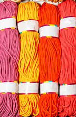 Skeins of polyester cord in bright pink, red, yellow and crimson colors.