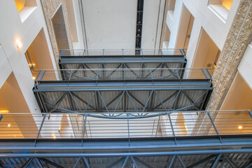 Three bridges in an office building spanning corridors over mezzanine with exposed structural steel deck elements, steel railings, nobody